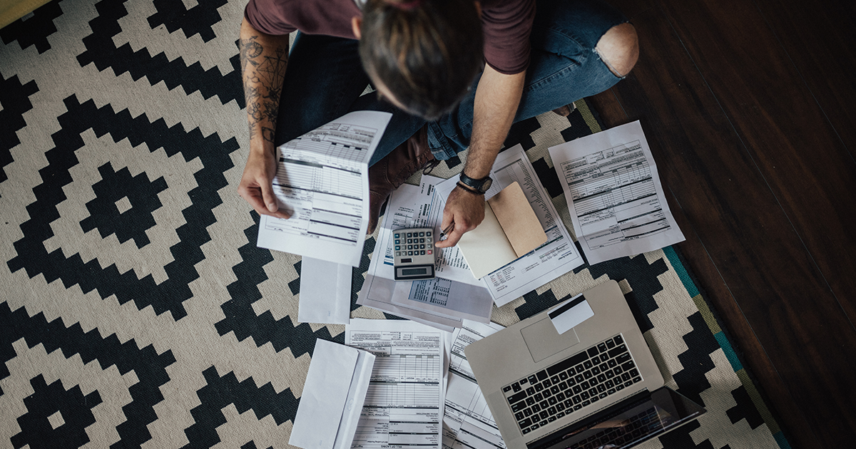 Man, sitting on floor, calculates bills